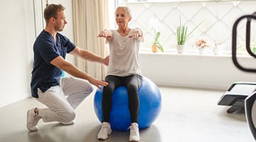 Physiotherapist working with senior on balance and core strengthening