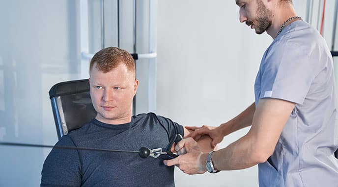 Man improving arm strength with the assistance of a healthcare worker